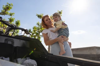 Eine Frau steht mit ihrem Sohn auf dem Arm hinter dem FS200 Life.