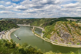 Blick auf den Rhein und die Loreley von einem Berg aus. Im Wasser fährt ein Schiff.