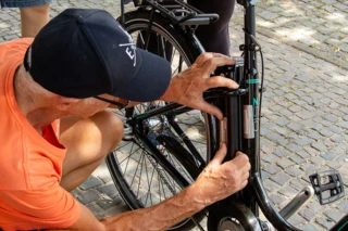 Ein Mann klebt den Aufkleber mit dem Code auf den Fahrradakku.