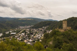 Bild von einer kleinen Stadt. Rechts auf dem Berg steht eine Burg. Links ist in der Ferne ein Fluss zu erkennen.